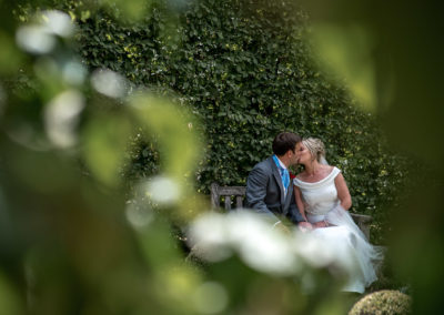 bride and groom secretly kissing, summer wedding photography