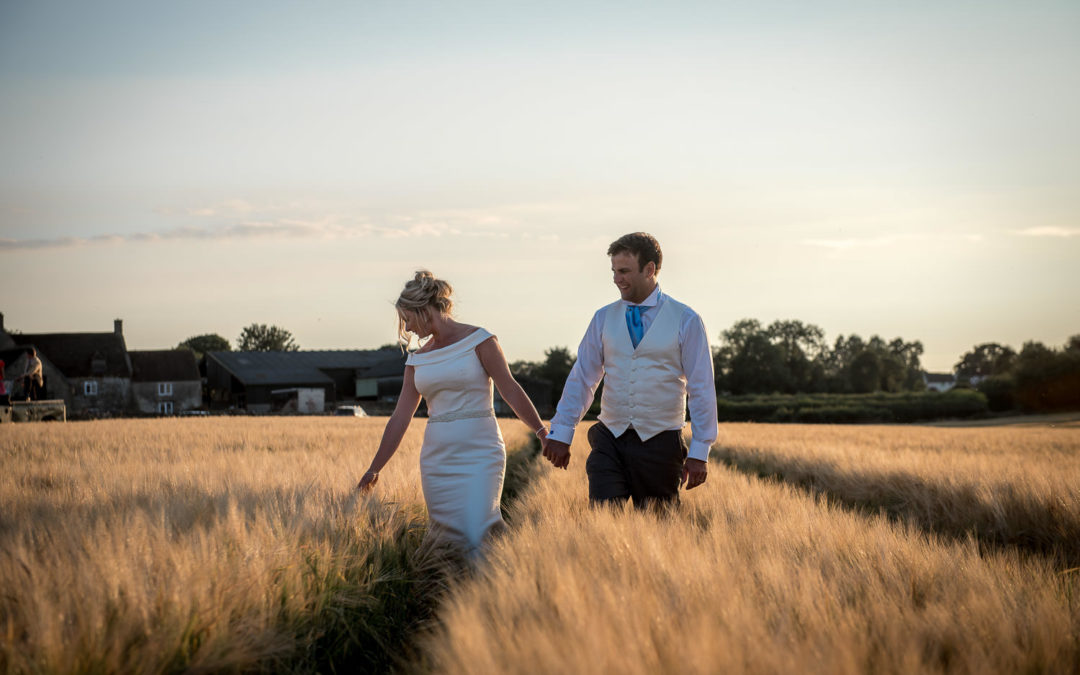 bride and groom walking through golden corn field at sunset, bath wedding photographer