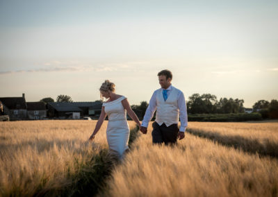 bride and groom walking through golden corn field at sunset, bath wedding photographer