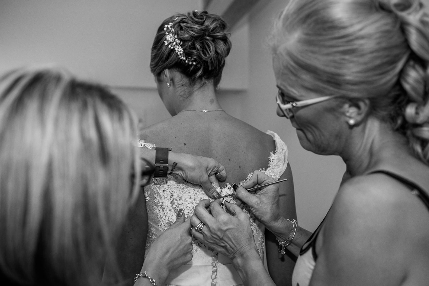 mother of the bride helping bride with her wedding dress