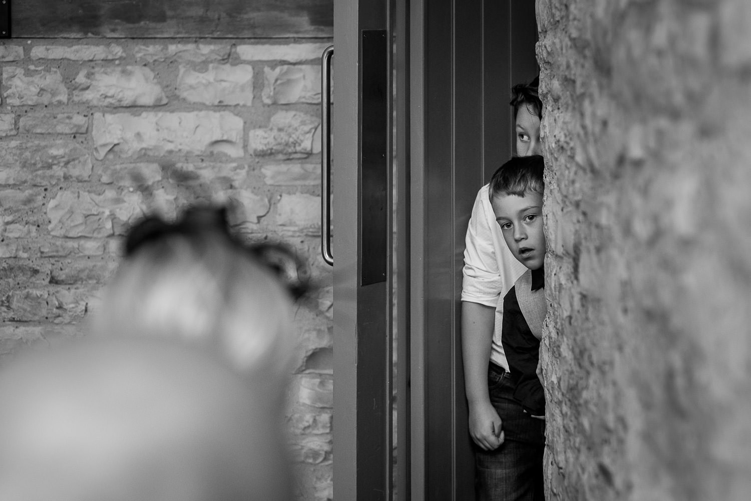 children looking around the corner at wedding reception