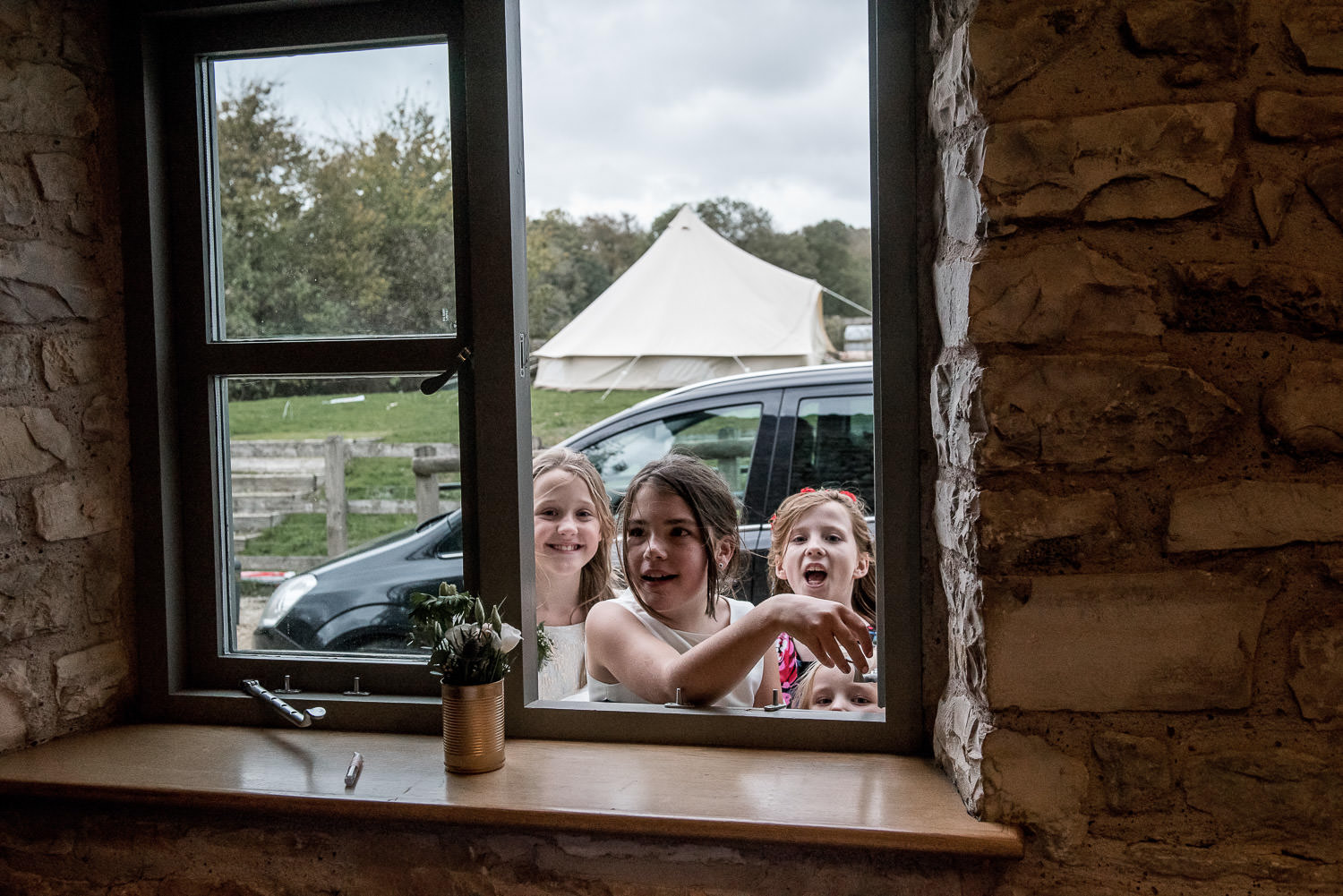 flower girls looking through a window at the wedding reception