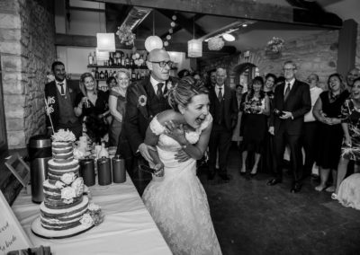 bride and groom having fun cutting the cake